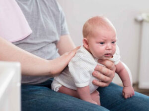 Image: Smiling baby wrapped in a blanket, demonstrating tips to prevent hiccups. Comfort and care.